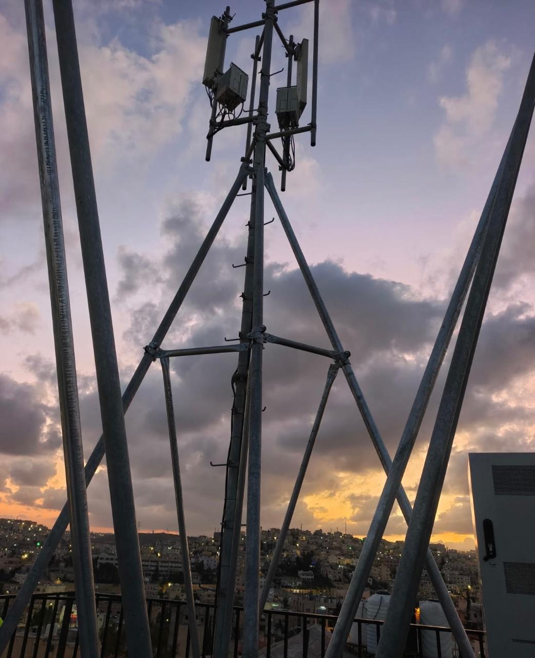 NTSC rooftop telecom tower silhouetted against a sunset sky over Amman